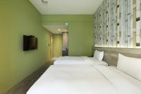 two beds in a room with green walls at KUN Hotel in Taichung