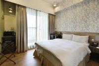 a bedroom with a large white bed and a window at KUN Hotel in Taichung