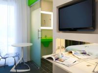 a room with a tv and a bed with a table at ibis Styles Nivelles in Nivelles