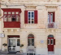 un edificio con ventanas rojas y un reloj en él en Two Pillows Boutique Hostel, en Sliema
