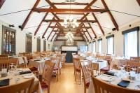 a banquet hall with tables and chairs and a screen at Gîte du Mont-Albert - Sepaq in Sainte-Anne-des-Monts
