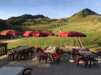 Un grupo de mesas y sillas con sombrillas. en Hôtel les skieurs, en Bellevaux