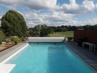a large swimming pool with a heat pump in a backyard at Le sentier des étangs in Barsy