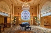 开罗开罗第一居所四季酒店的一个宽敞的房间，里面摆放着一架钢琴和一扇彩色玻璃窗。