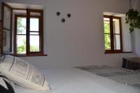 a white bedroom with two windows and a bed at Mas Mialou in Saint-Jean-du-Gard