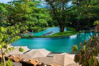 a swimming pool with chairs and umbrellas next to a river at Capella Singapore in Singapore