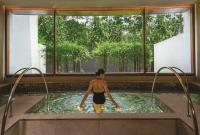 a man in a hot tub in a room with a window at Capella Singapore in Singapore