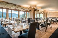 a restaurant with tables and chairs and mountains in the background at Hotel Mareo Dolomites in San Vigilio Di Marebbe
