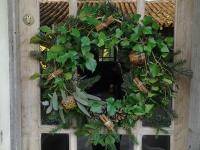 a christmas wreath on a door with a window at Les Hotes Des Guillemets in Laglorieuse