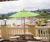 een picknicktafel met een groene parasol op een balkon bij The Heritage Hotel in Torquay