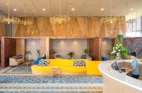 a lobby with a yellow couch and tables and chairs at Eastin Ashta Resort Canggu in Canggu