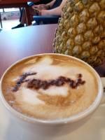 a cup of cappuccino with a face drawn on it at Seahouse Bali Indah Beach Inn in Kuta