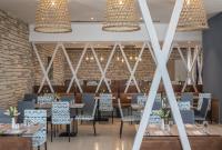 a dining room with tables and chairs and a brick wall at Falkensteiner Club Funimation Borik in Zadar