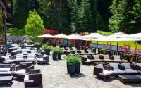 a patio with tables and chairs and umbrellas at Lux Garden Hotel in Azuga