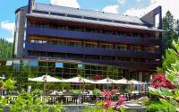 a building with tables and umbrellas in front of it at Lux Garden Hotel in Azuga