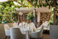 a restaurant with white tables and chairs and plants at Hotel Ansitz Plantiz in Merano