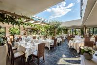 a restaurant with white tables and chairs and large windows at Hotel Ansitz Plantiz in Merano