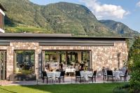 a patio with tables and chairs and mountains in the background at Hotel Ansitz Plantiz in Merano