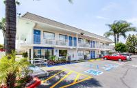 Un edificio con un coche rojo estacionado en un estacionamiento. en Motel 6-Rosemead, CA - Los Angeles, en Rosemead