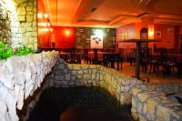 ein Restaurant mit einer Steinmauer sowie Tischen und Stühlen in der Unterkunft Hotel Vila Ivanković in Buna