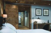 a bedroom with a wooden door leading into a room at Chalet-Hôtel La Marmotte, La Tapiaz &amp; SPA, The Originals Relais (Hotel-Chalet de Tradition) in Les Gets