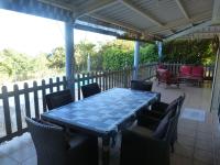 einen blauen Tisch und Stühle auf einer Veranda mit einem Tisch und Stühlen in der Unterkunft Villa Flamboyant in Le Portail