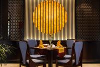 uma sala de jantar com mesa, cadeiras e uma grande luminária em Laluna Hoi An Riverside Hotel & Spa em Hoi An