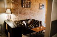 a living room with a leather couch and a brick wall at La Suite Romantique avec Jacuzzi au Cœur de Perpignan in Perpignan