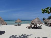 a beach with chairs and straw umbrellas and the ocean at Nice Sea Resort in Srithanu