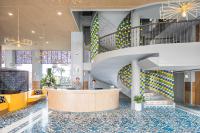a lobby with a staircase and two people standing at a counter at Eastin Ashta Resort Canggu in Canggu