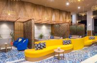 a lobby with yellow and blue furniture and tables at Eastin Ashta Resort Canggu in Canggu