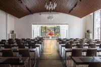 a room with tables and chairs and a stained glass window at AMERON Hamburg Hotel Speicherstadt in Hamburg
