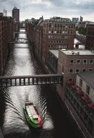 a boat traveling down a river under a bridge at AMERON Hamburg Hotel Speicherstadt in Hamburg