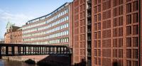 a tall brick building with a bridge next to a river at AMERON Hamburg Hotel Speicherstadt in Hamburg