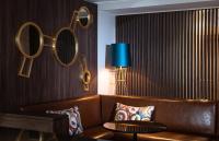 a living room with a brown couch and mirrors on the wall at AMERON Hamburg Hotel Speicherstadt in Hamburg