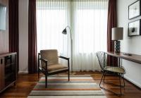a living room with a chair and a desk and a lamp at AMERON Hamburg Hotel Speicherstadt in Hamburg