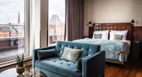 a bedroom with a blue couch and a bed and a window at AMERON Hamburg Hotel Speicherstadt in Hamburg