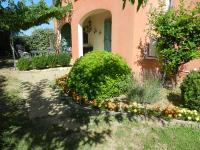a garden in front of a pink house with flowers at L&#39;Oliveraie in Draguignan