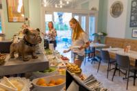 Une femme debout dans un restaurant avec un chien sur un buffet dans l'établissement Delight Deluxe Aparts, à Antalya