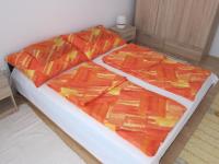 a bed with orange and yellow blankets on it at Erdélyi vendégház in Sárospatak