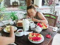 a woman sitting at a table with plates of fruit at Poppies Mirissa in Mirissa