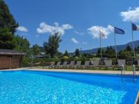 a swimming pool with chairs and flags on a resort at Logis Le Vernay in Autrans