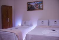 a bedroom with two beds with white sheets and a picture on the wall at Pousada Mama África in Conservatória