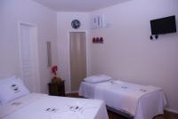 a room with two beds and a tv on the wall at Pousada Mama África in Conservatória
