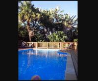 a swimming pool with a wooden fence and palm trees at Le four à pain in Saint-Philippe