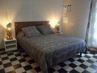 a bedroom with a bed with two lamps and a checkered floor at Le four à pain in Saint-Philippe