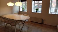 a table and chairs in a room with windows at Aalborg City Rooms ApS in Aalborg