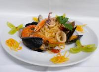 un piatto bianco di cibo con pasta e verdure di Hotel Continental a Pietra Ligure