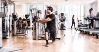 a man in a gym doing squats on machines at The Peninsula Chicago in Chicago
