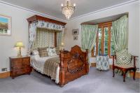 ein Schlafzimmer mit einem Holzbett und einem Kronleuchter in der Unterkunft Taldraeth - Old Vicarage Guest House in Penrhyndeudreath